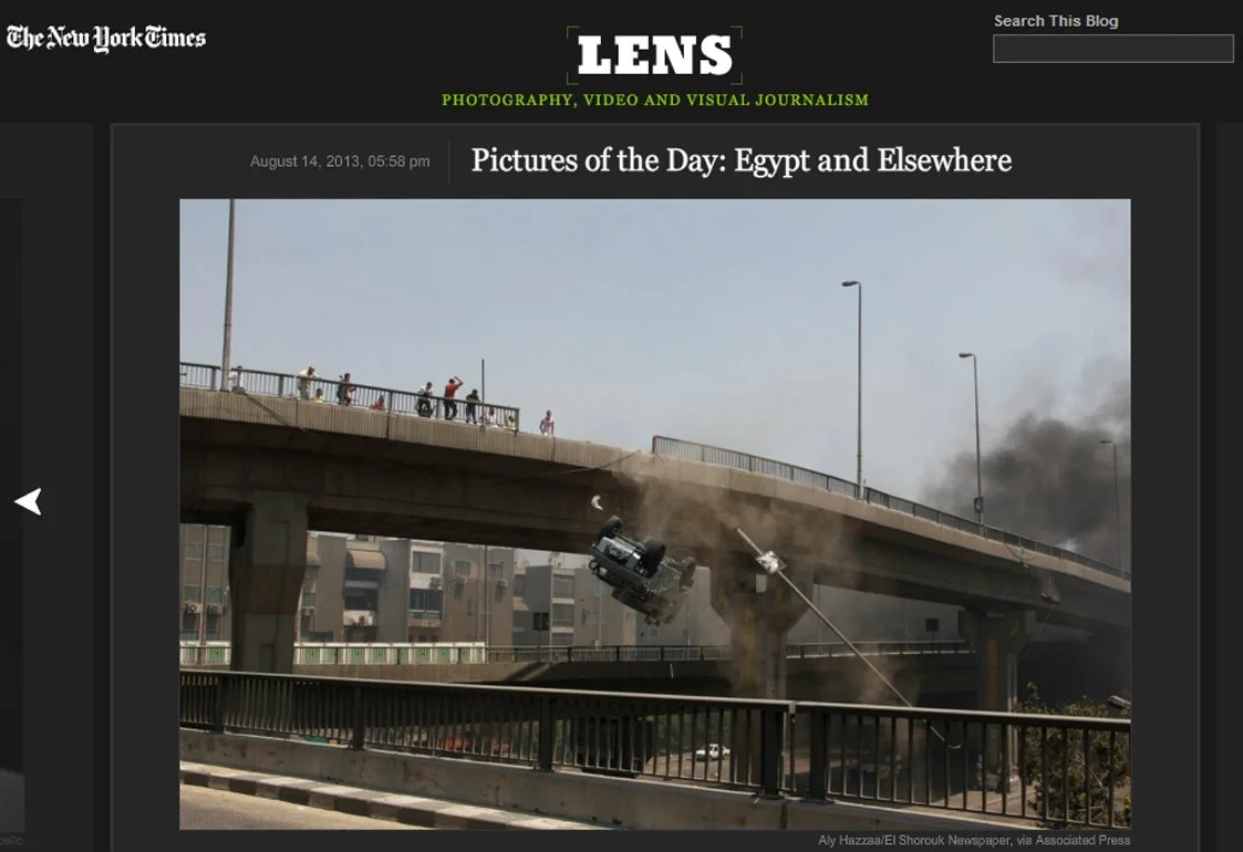 A police car has collided with a street lamp post on a bridge, causing the lamp post to bend and break, with debris falling, while smoke rises below the bridge in a city setting.