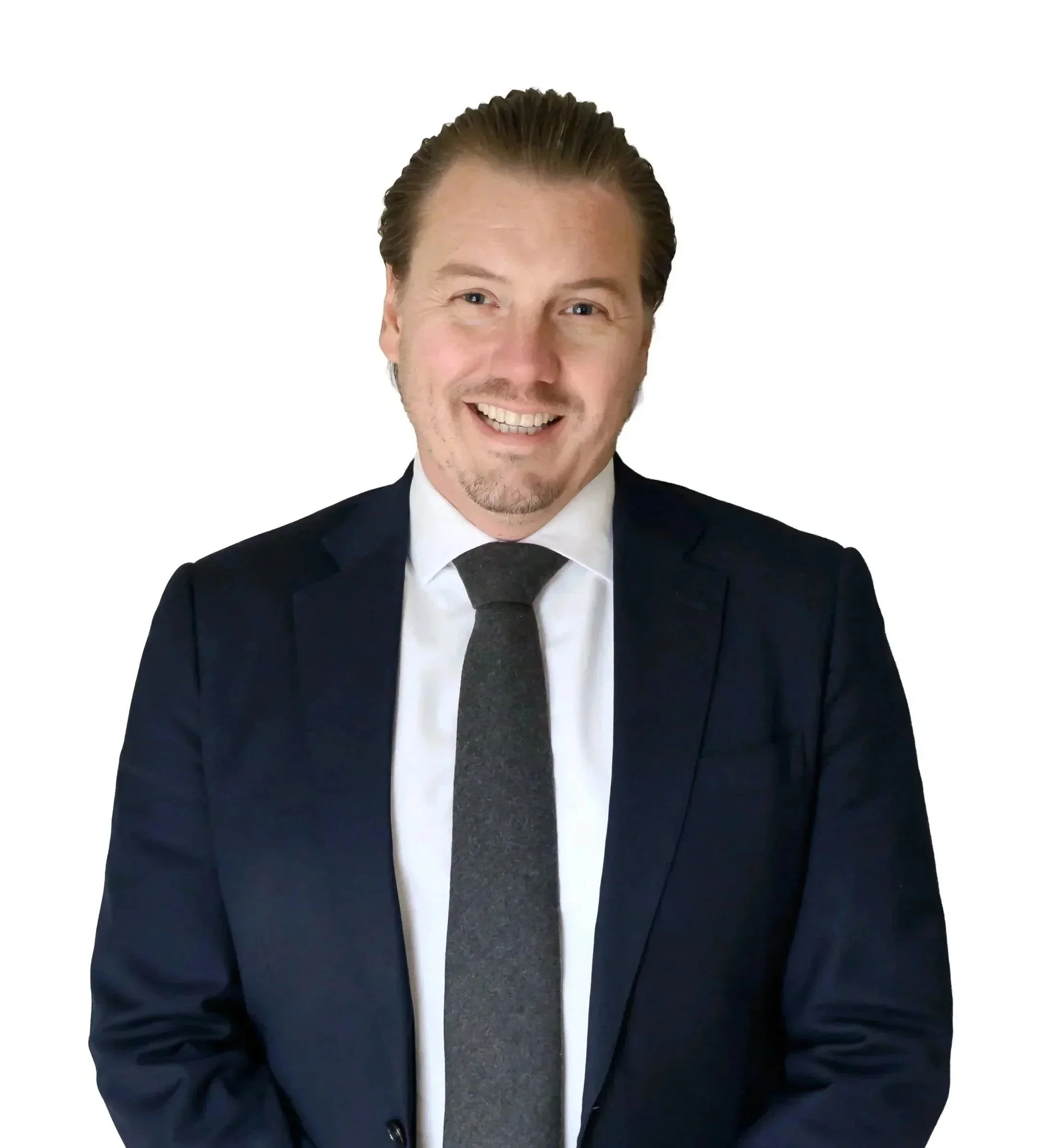 En glad man i mörk kostym och slips, poserar mot en vit bakgrund.