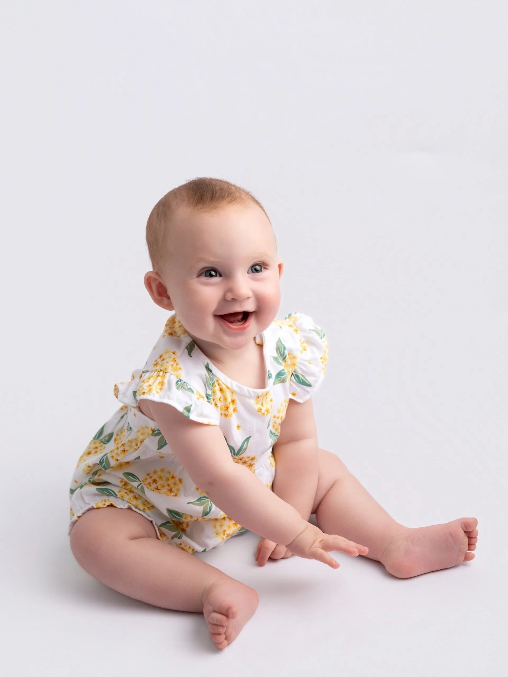 A baby sitting down smilling