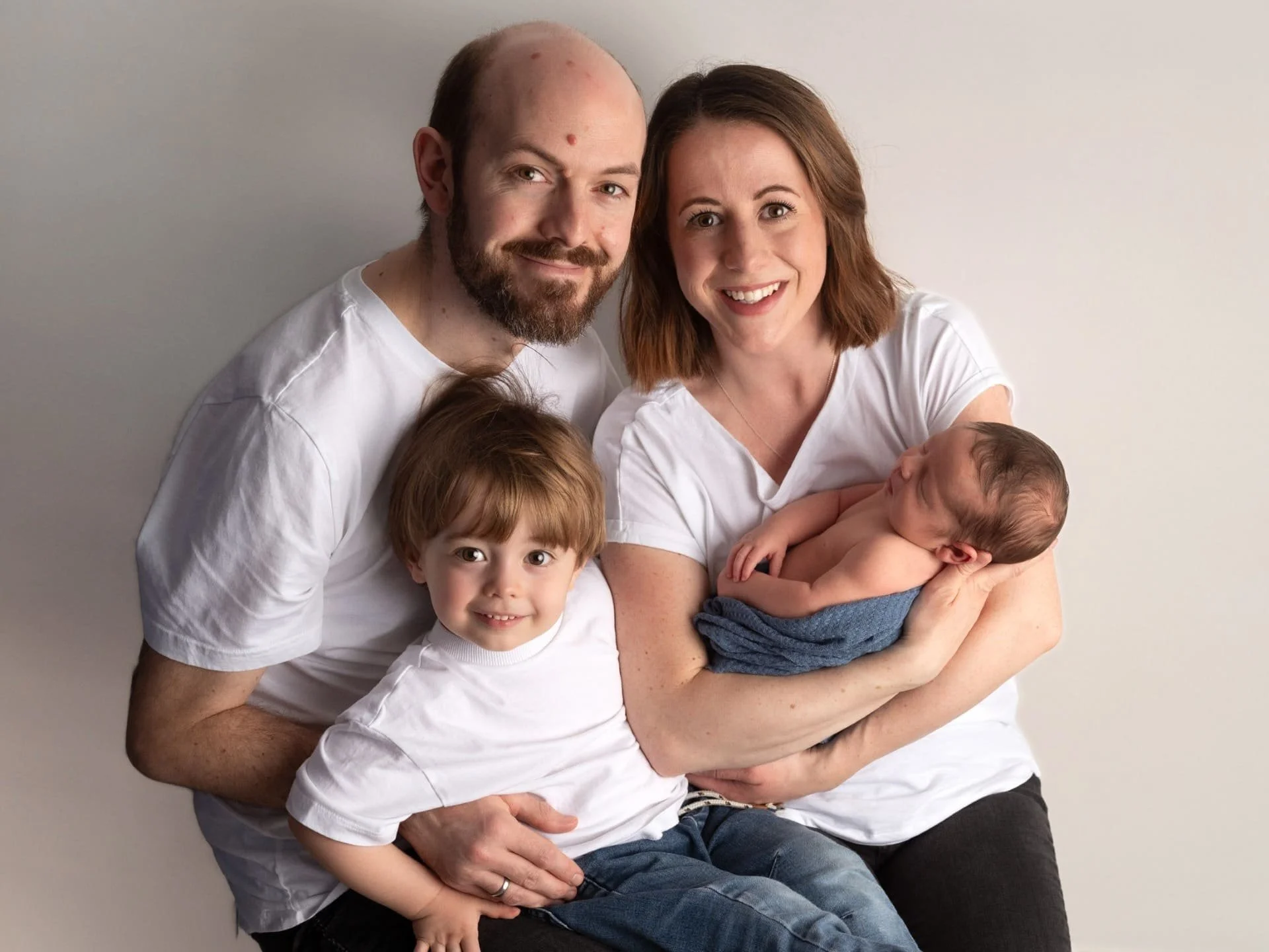 A family photo of a man, woman, boy and their new child 