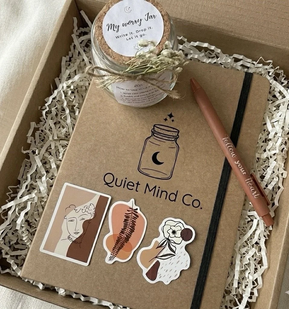 A gift box contains a jar labeled 'My worry jar,' a brown notebook with 'Relax your mind' written on a pen, and three decorative stickers on the notebook.