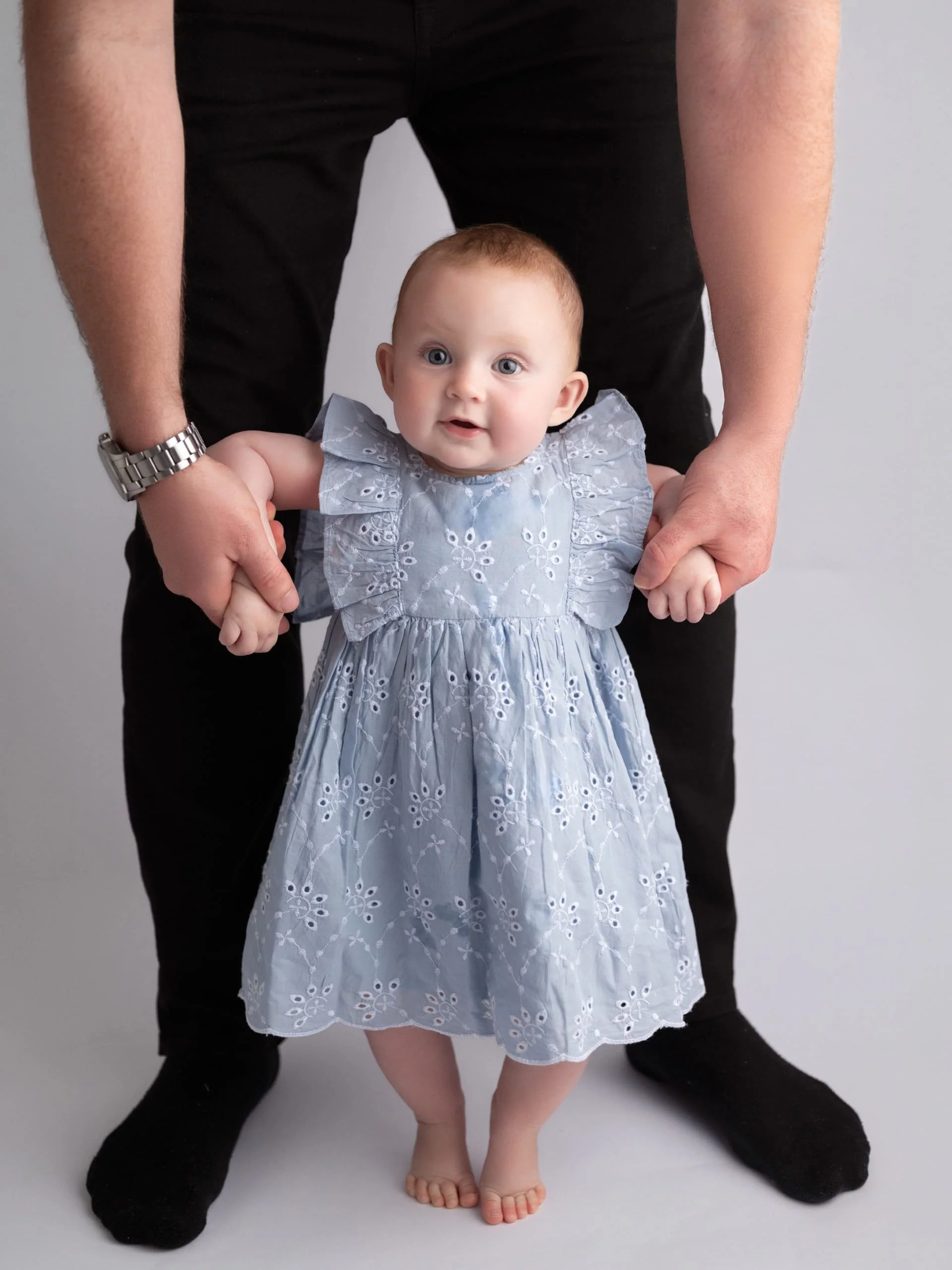 A baby standing up and being held