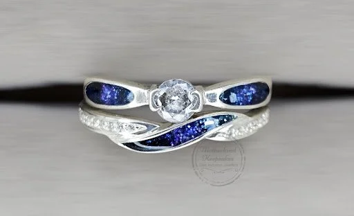 A silver ring with dark blue galaxy-themed inlays and a central clear gemstone.