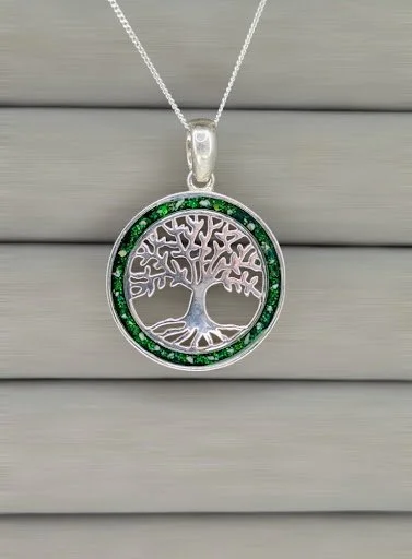 Silver necklace with a circular pendant featuring a tree design surrounded by green gemstones.