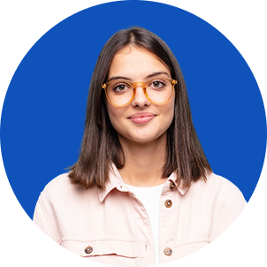 A young woman with brown hair, wearing glasses and a white jacket, smiling against a blue background.