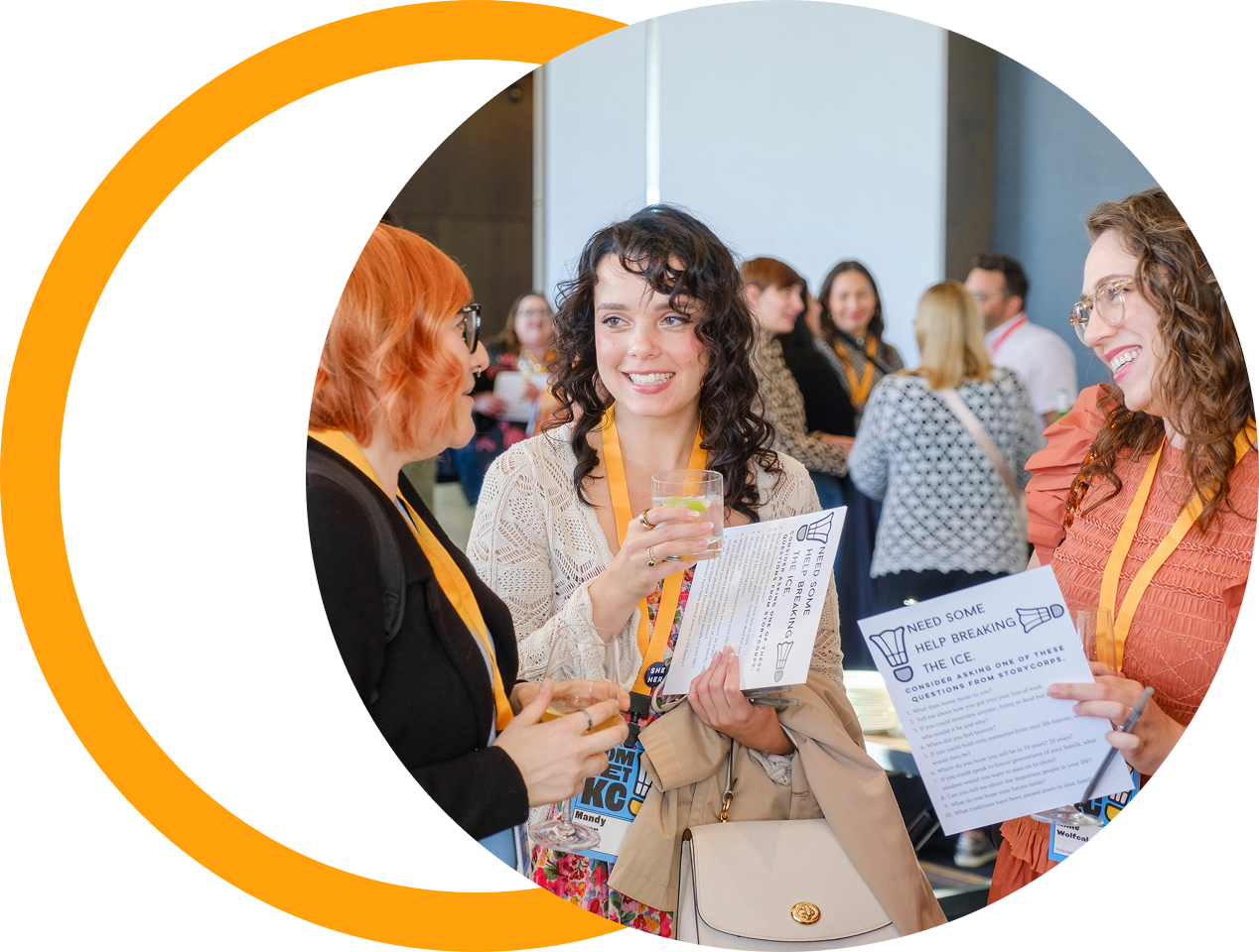 A group of women at a networking event, talking and holding drinks and flyers, with a background of more attendees in a conference room.