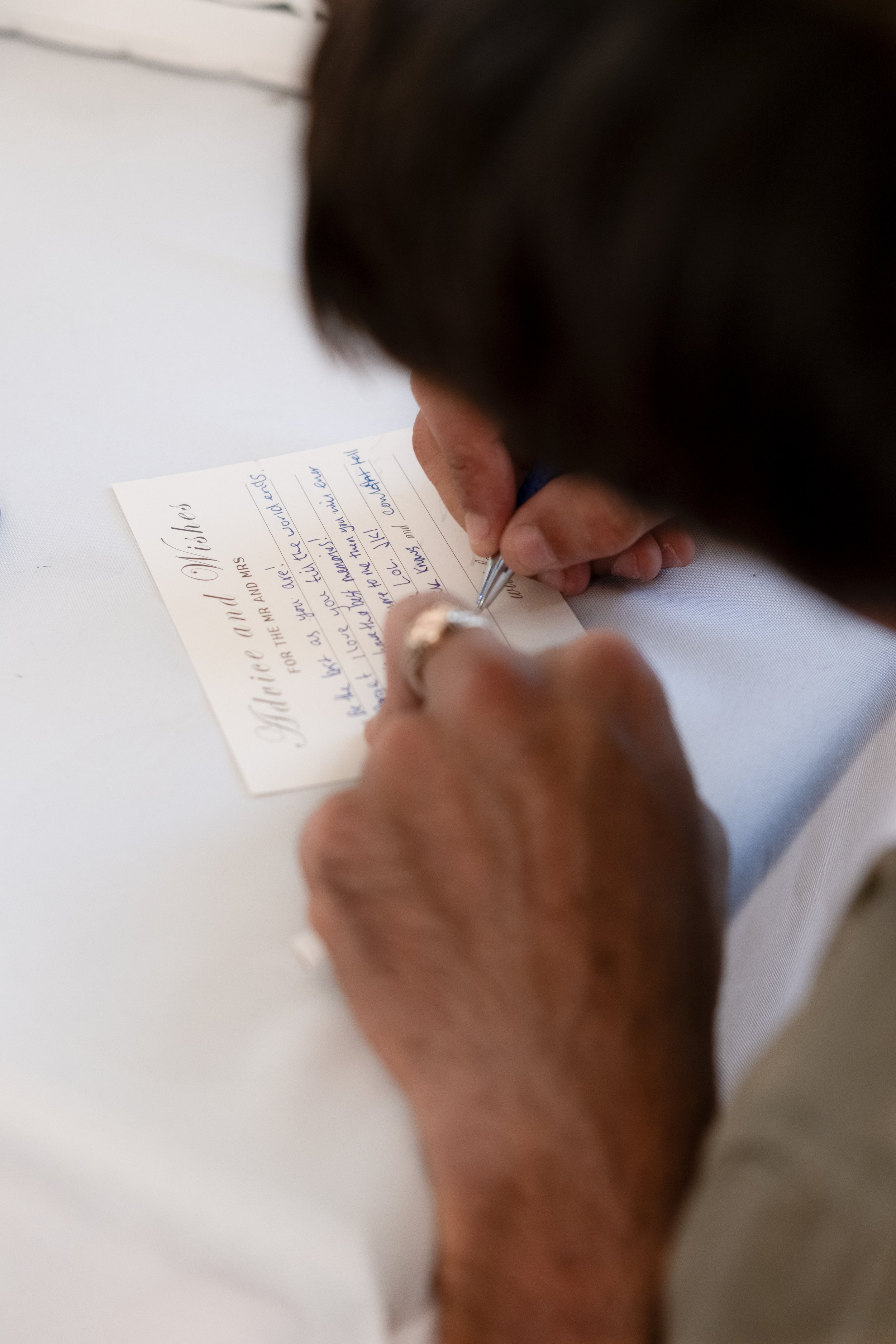 A person writing a handwritten note on a piece of paper with a pen.