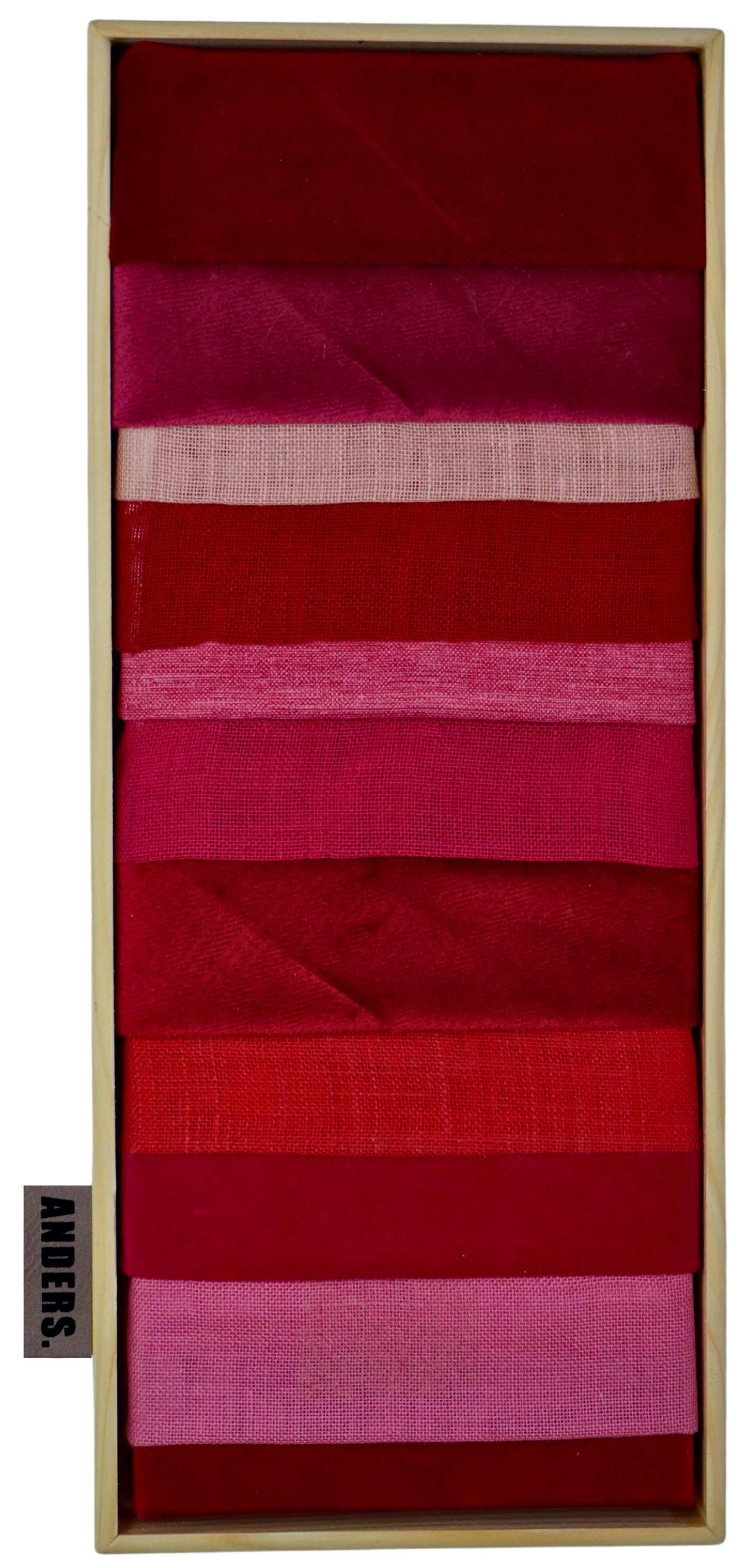 Verschiedene rote und pinke Stoffbänder in einer Holzkiste angeordnet. UNIKAT