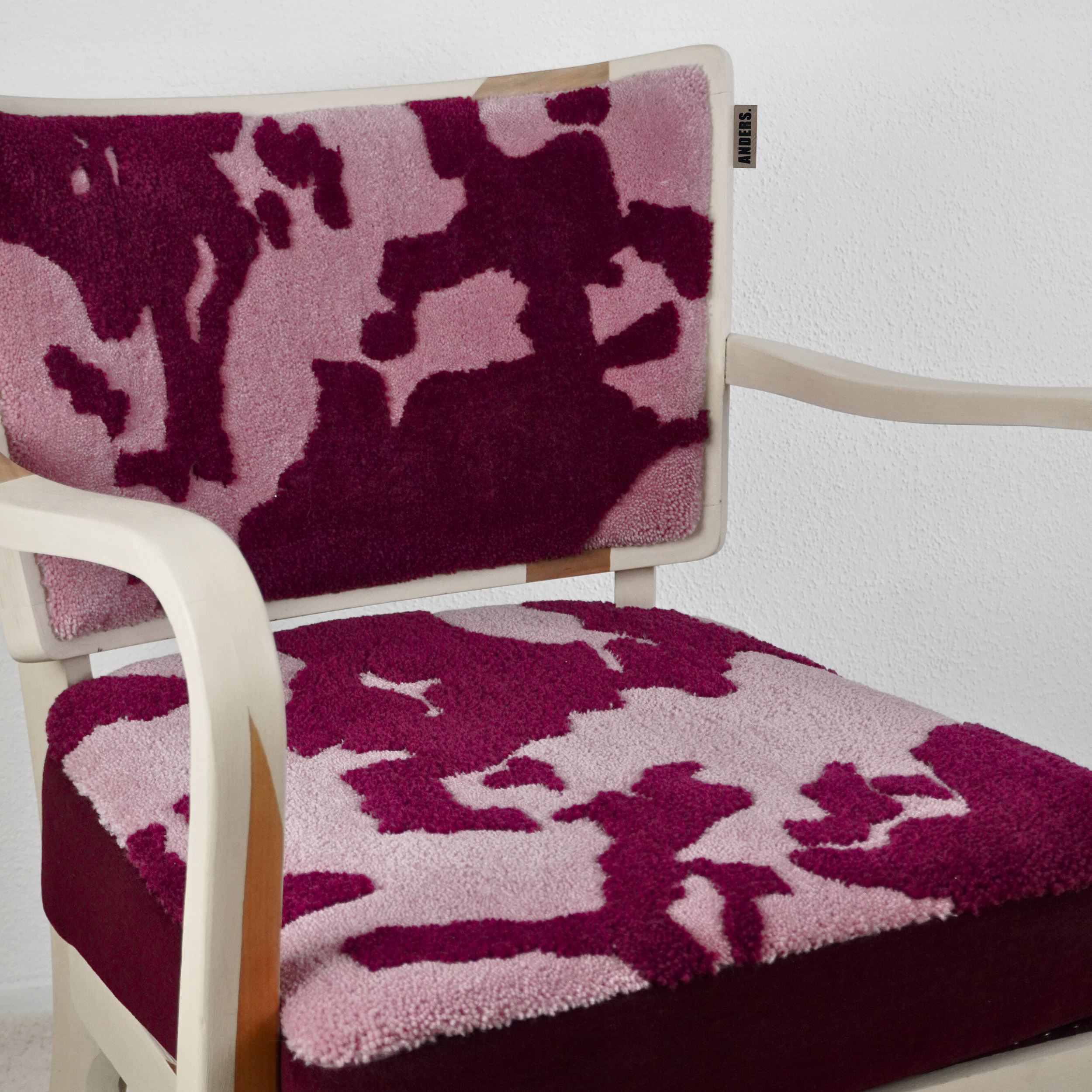 Ein Stuhl mit einem pinken und dunkelroten Teppich, der eine Weltkarte darstellt.