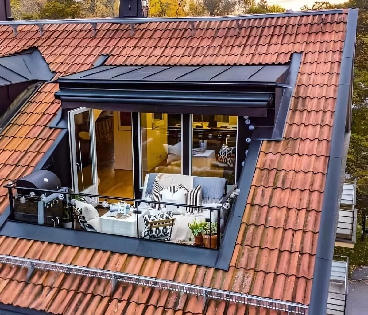 Sunken roof terrace balcony cut into a tiled roofline with glass doors to the living space