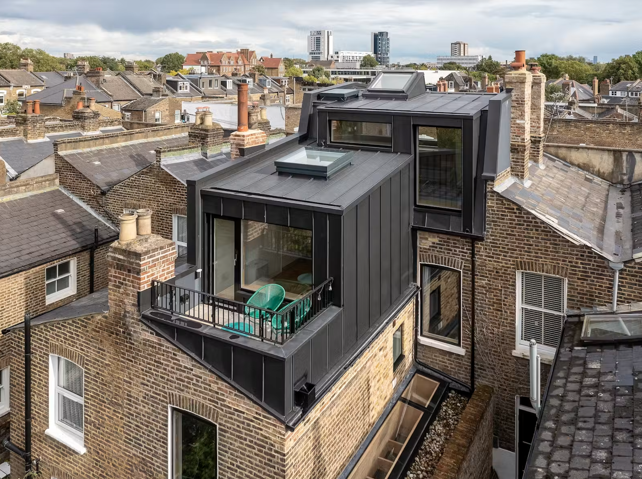 Zinc-clad rooftop loft extension with glass balcony overlooking London terrace rooftops