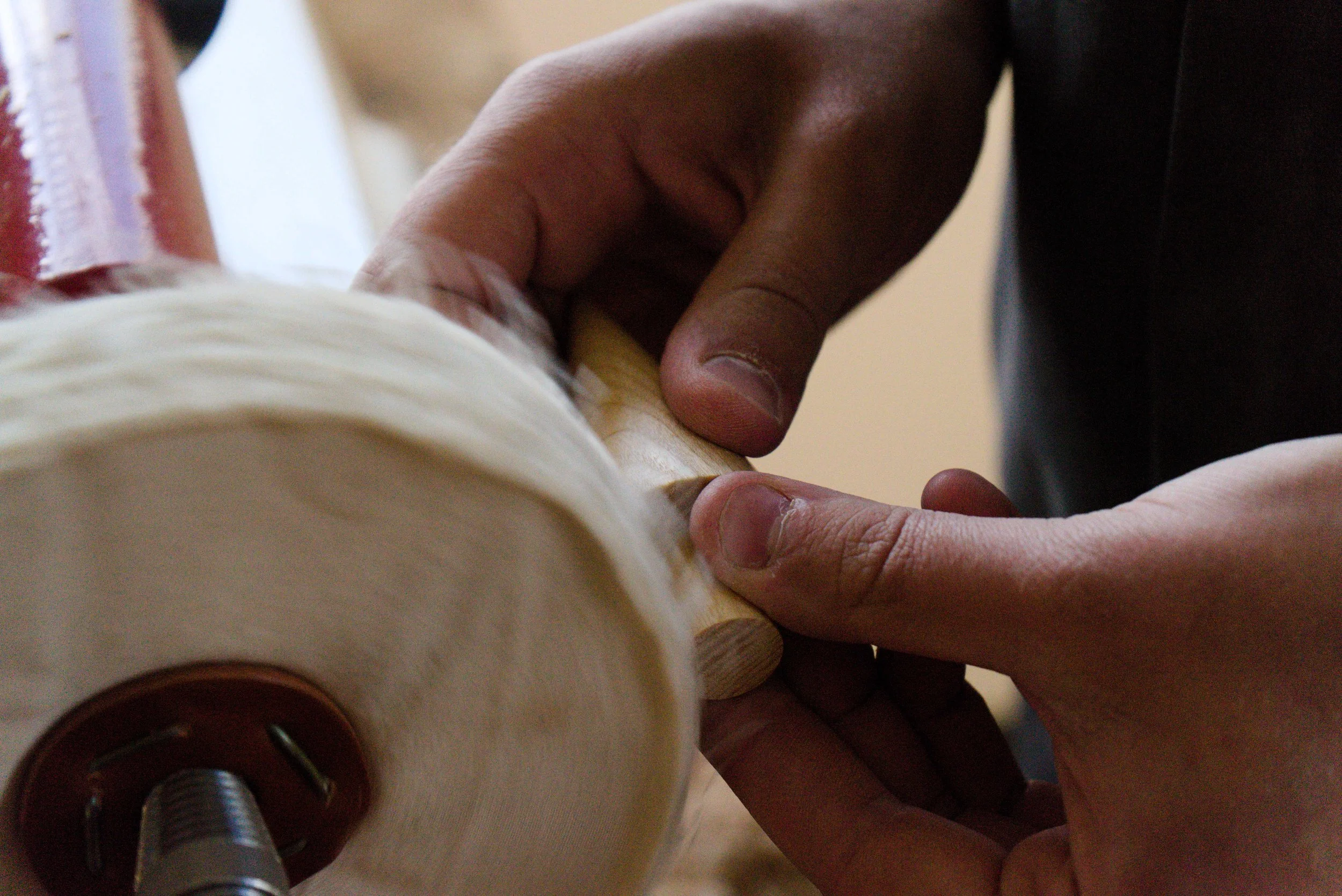 A person using a woodworking tool on a wooden piece to carve or shape it.