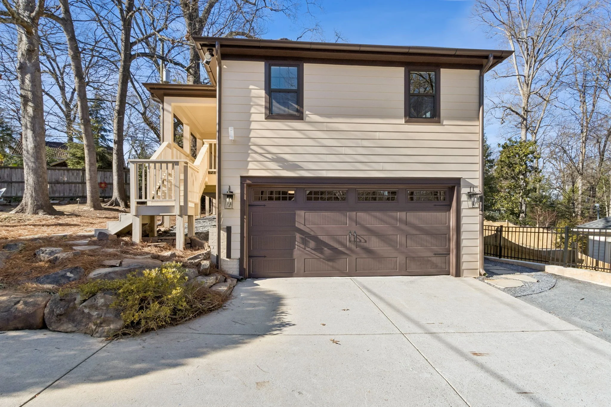 Royal Custom Homes & Remodeling restored & renovated this historic Druid Hills carriage house. The house has a dark garage door, a light-colored wooden staircase leading to the front porch, with a small porch light beside the door.
