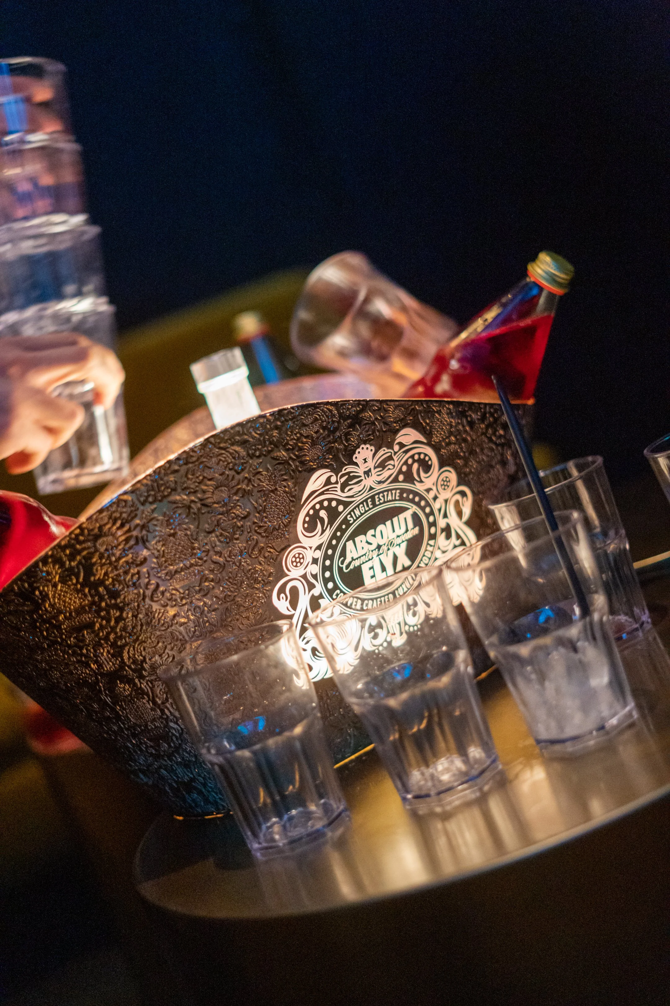 Bar mit Gläsern, eine große dekorative Absinth-Schale, und eine Flasche mit rotem Getränk. Schirmchen im Glas. Spiegelung auf Tisch