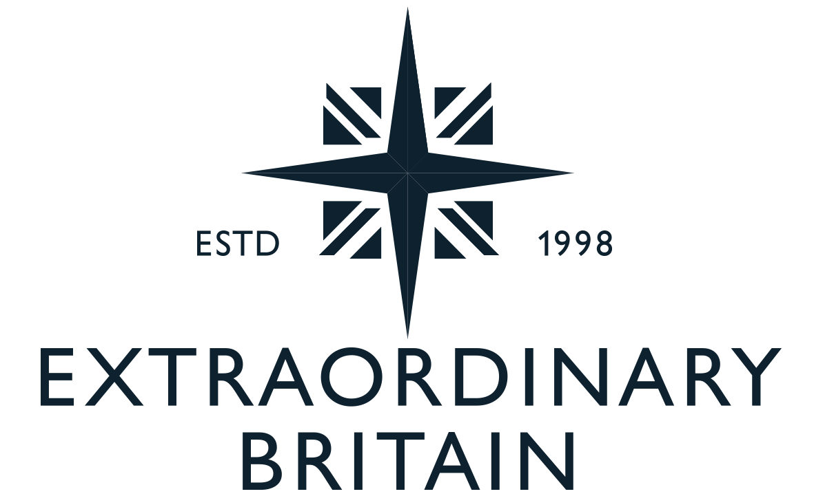 Un logo avec une étoile à quatre branches entourée de drapeaux britanniques, le texte "ESTD 1998" et "Extraordinary Britain" en dessous.