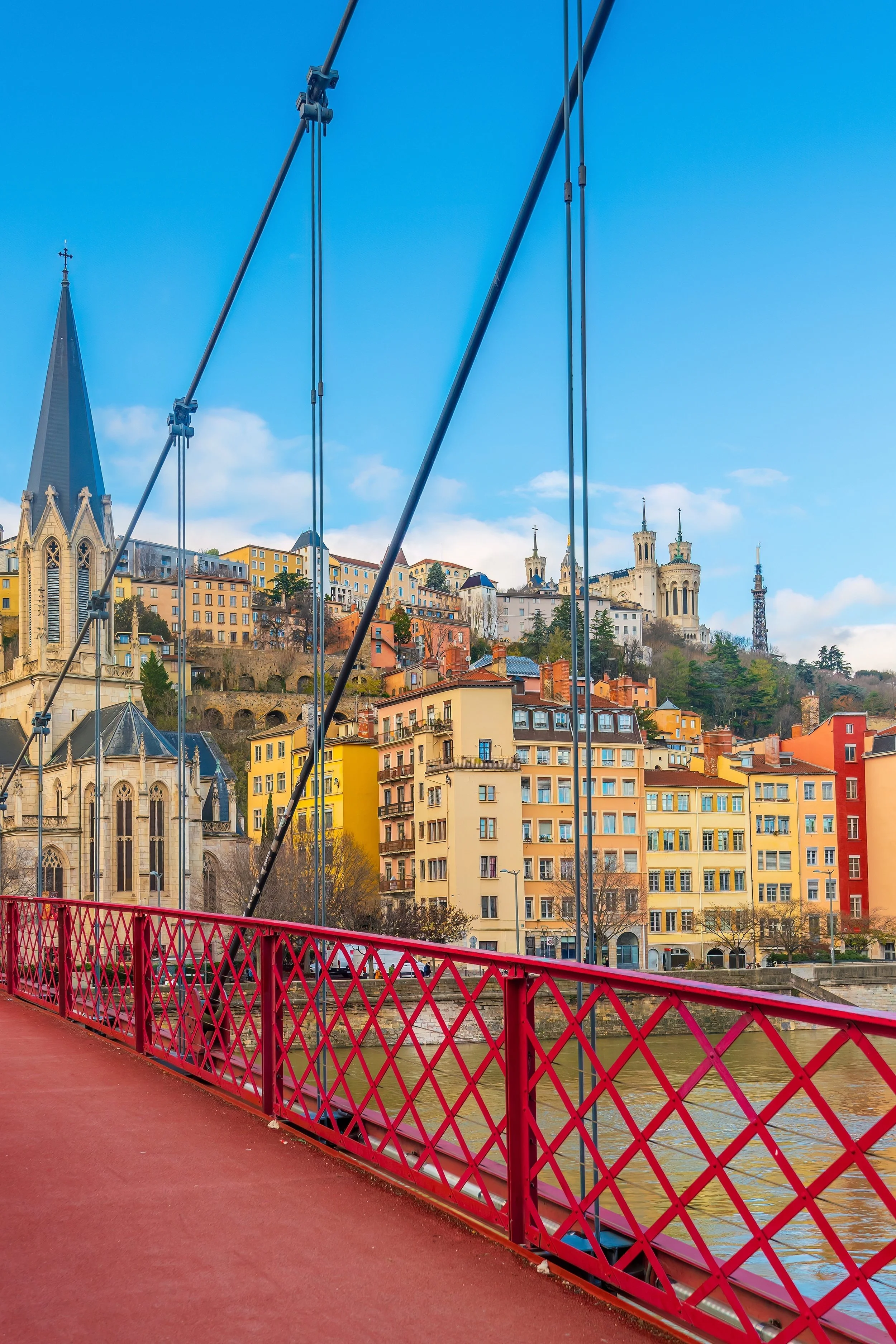 A majestic, historic white castle with four tall peaked spires, surrounded by trees, under a clear blue sky.