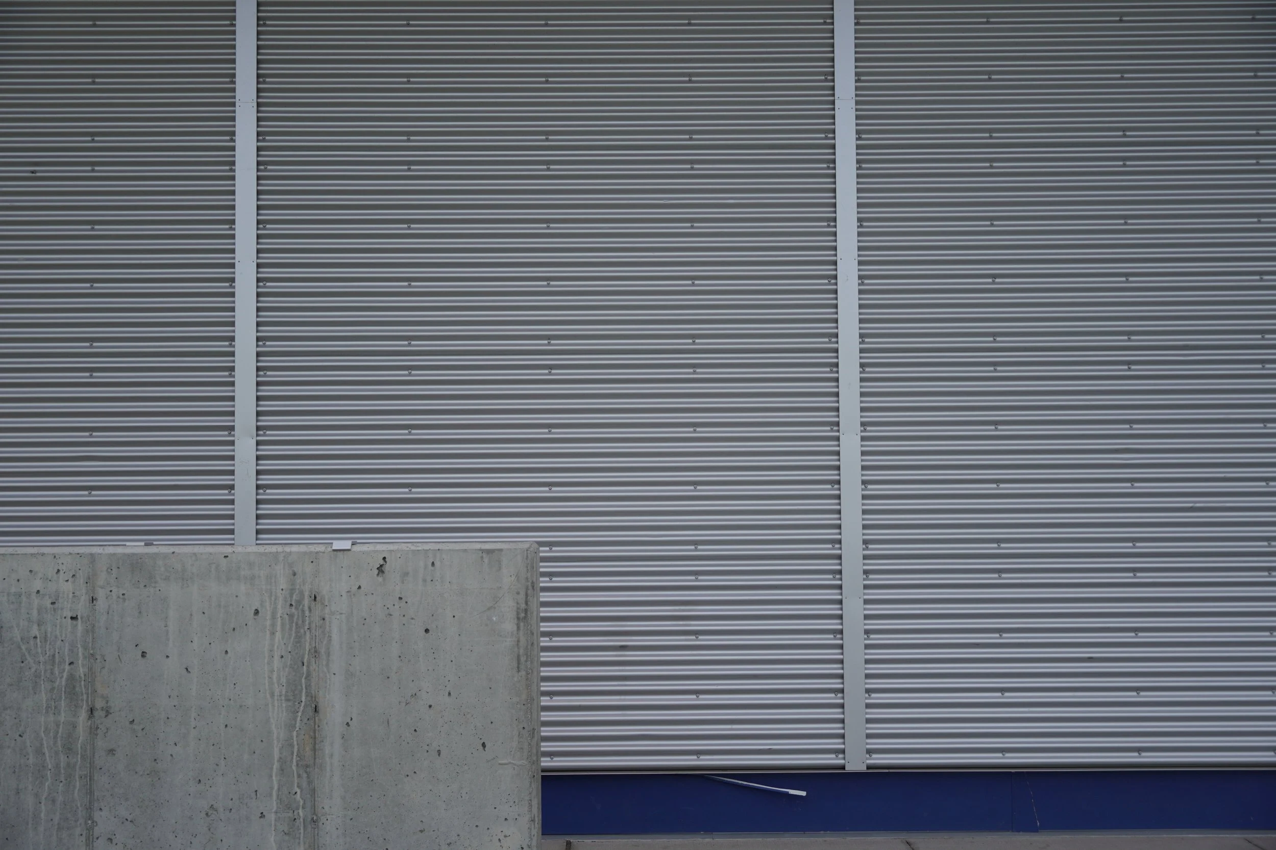 Architectural concrete, corrugated steel, and cement board layered for high durability and elevated design at Lambert Field sports complex.