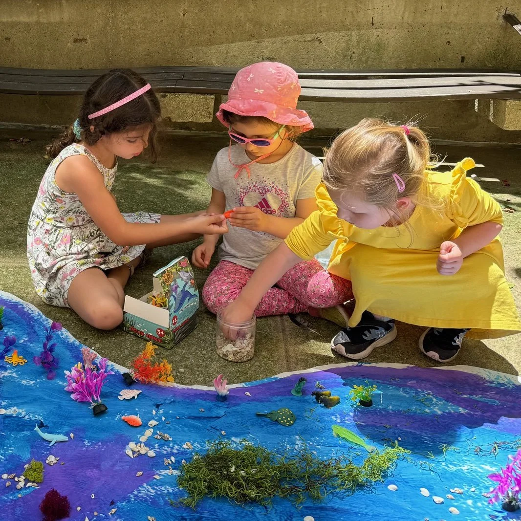 Three children, girls, creating an under water landscape together, exploring and playing.