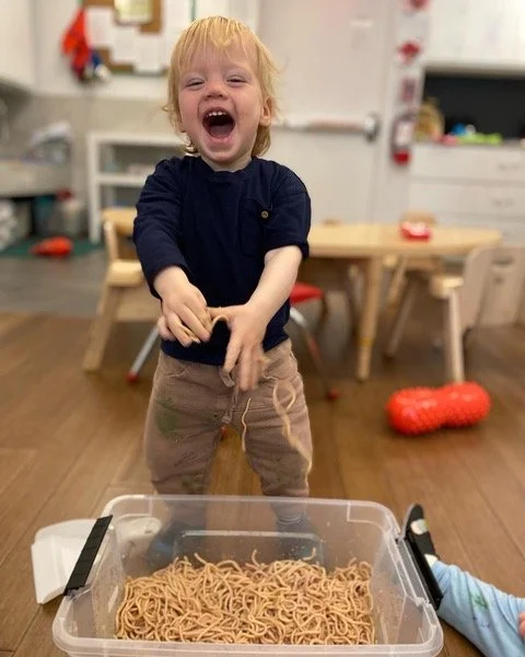 Toddler playing with spaghetti