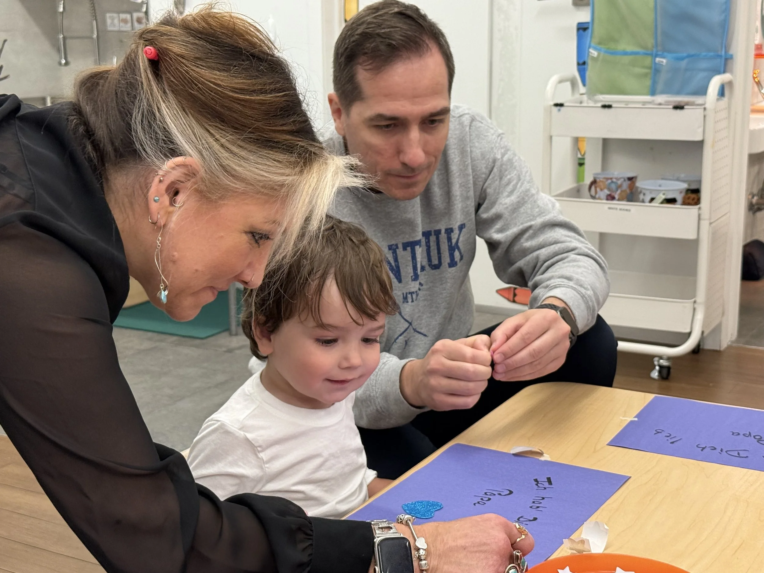 young boy with his dad and a teacher creating a picture together