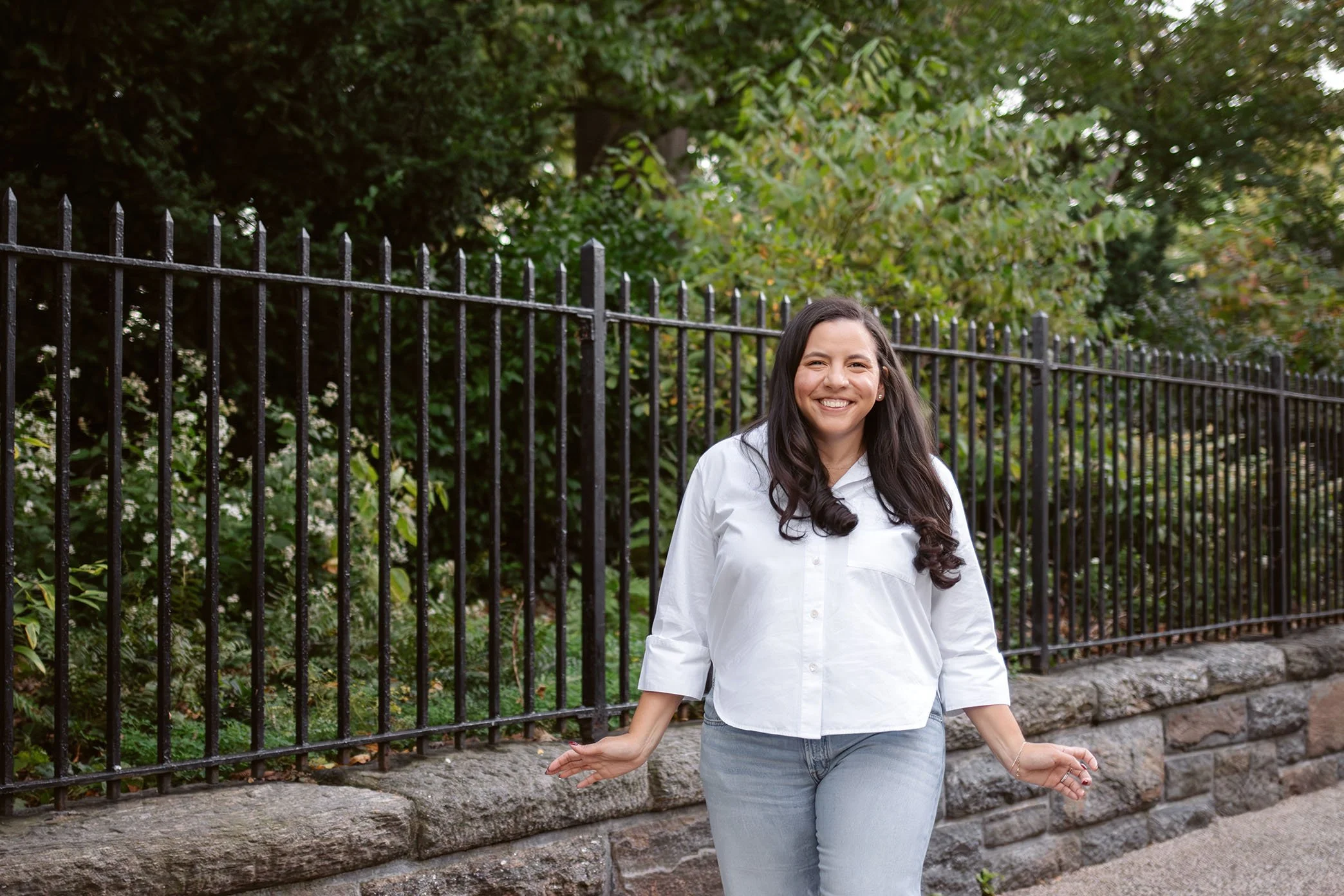 Jessica stands outside and smiles in a white button-up