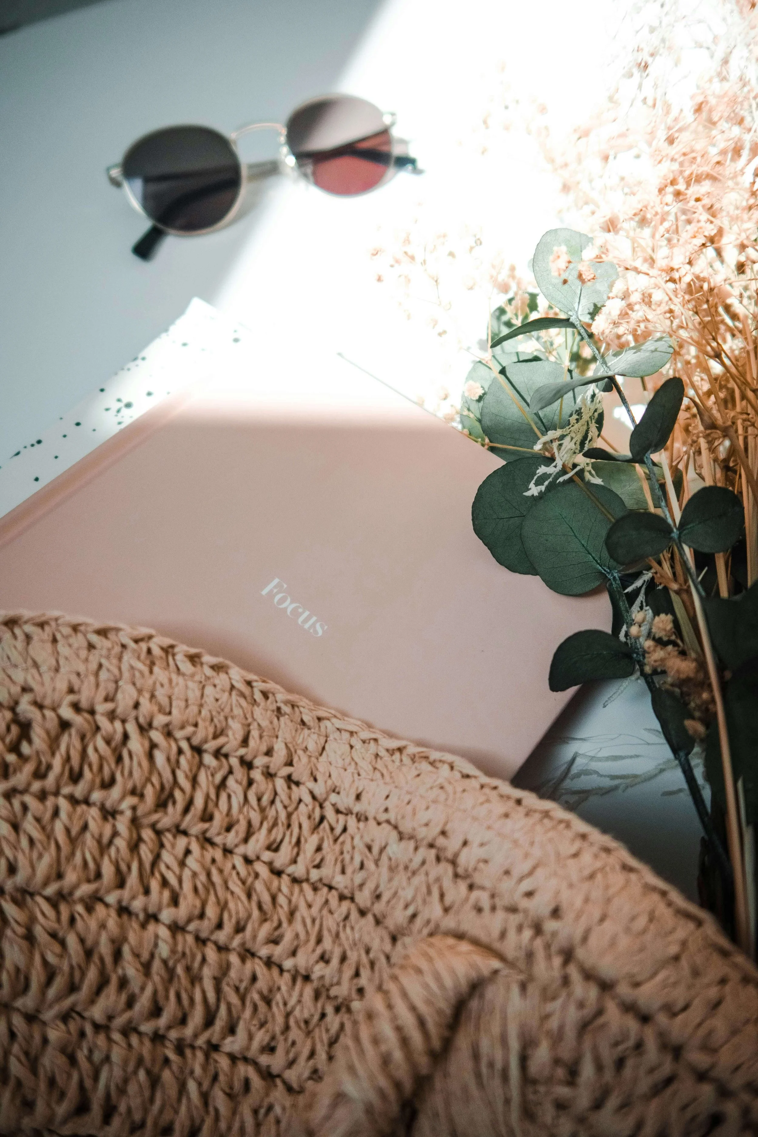 Pink notebook reading "Focus," surrounded by flowers, a bad, and a pair of glasses