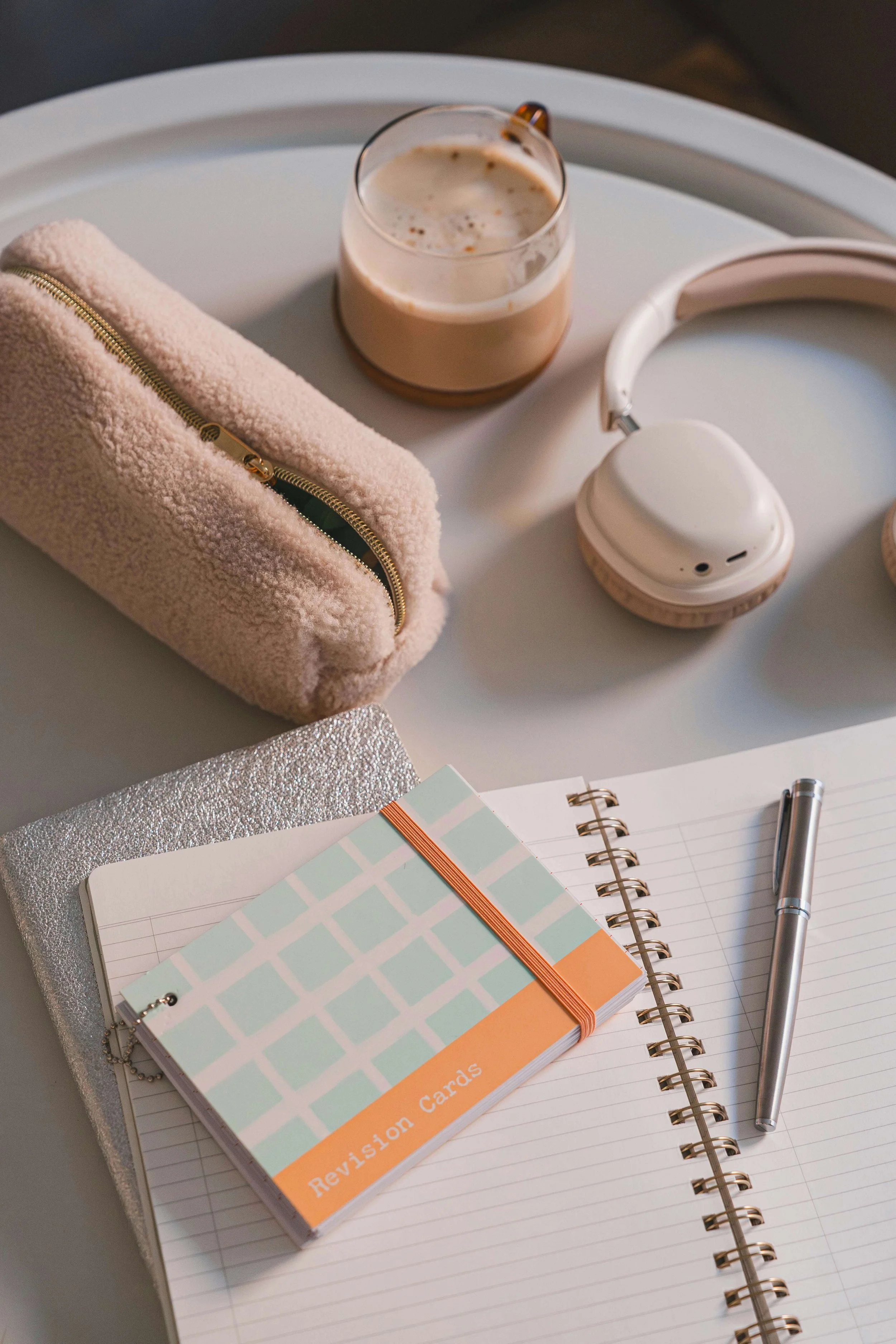 Coffee, pencil poach, headphones, two notebooks, and a ring of index cards