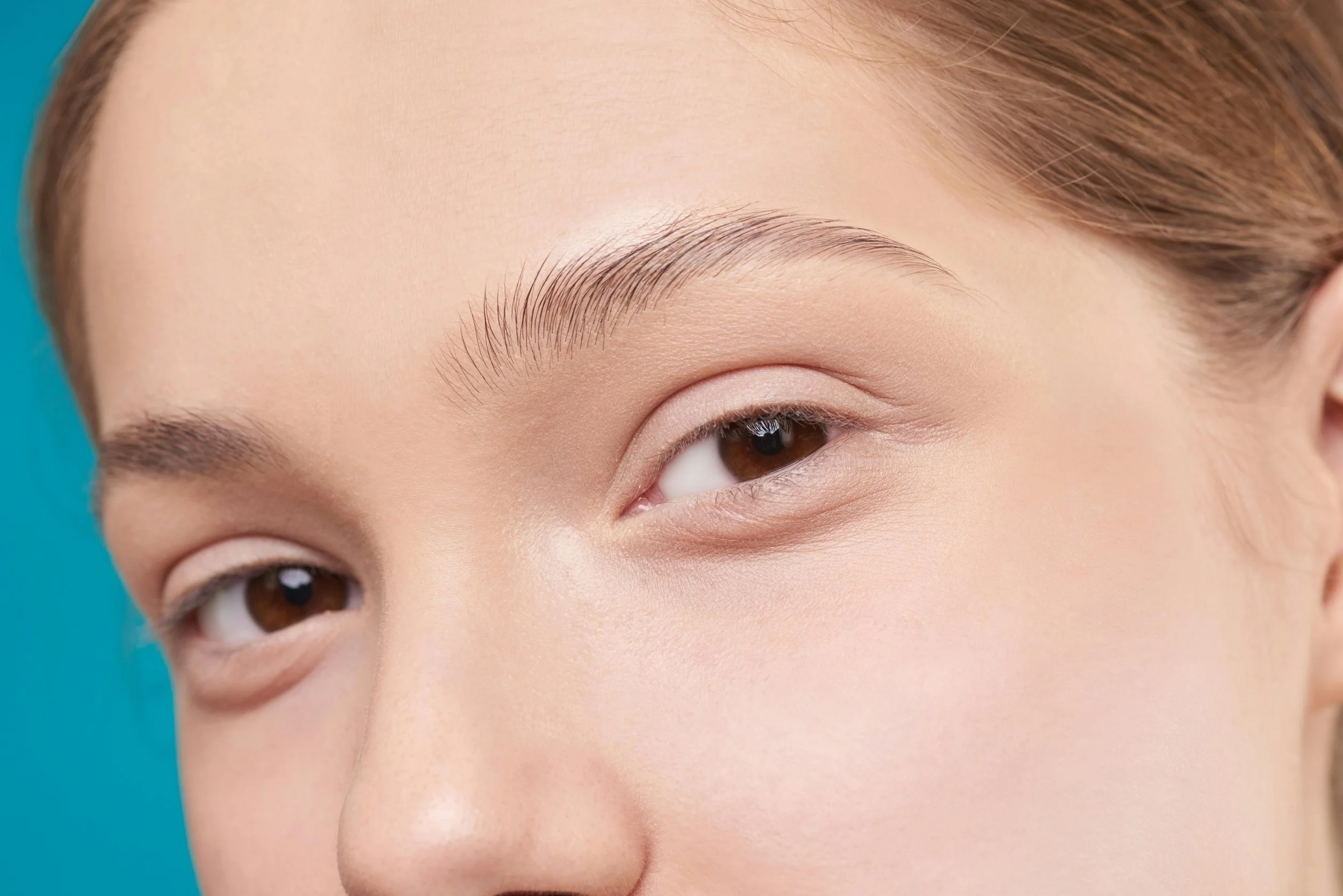 Close-up of a woman's face, focusing on her eye and eyebrow, with smooth skin and natural makeup.