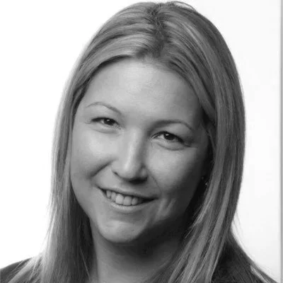 Black and white portrait of a woman with long, light-colored hair, smiling and facing slightly to the right.
