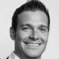 Black and white photo of a smiling man with short dark hair