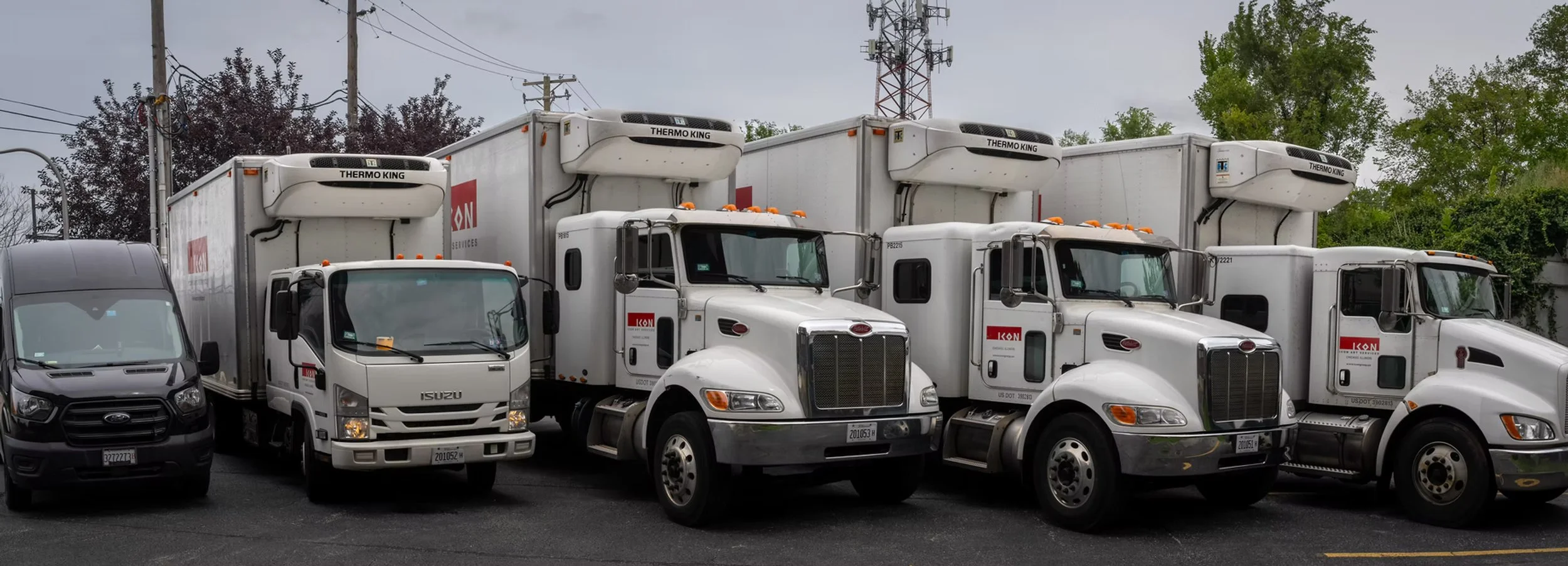 Six trucks parked side by side, including an Isuzu van and five large semi-trailers with refrigerated units, branded with 'KON' and 'Thermo King'.