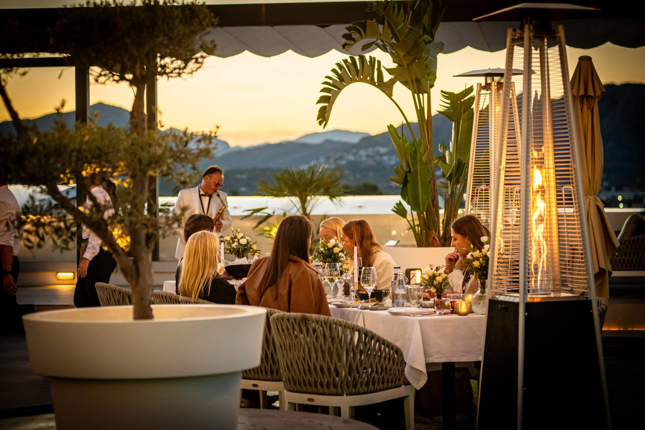 Several persons seated at a dinner table in El Balcón de la Sella restaurant at Syncrosfera Hotel