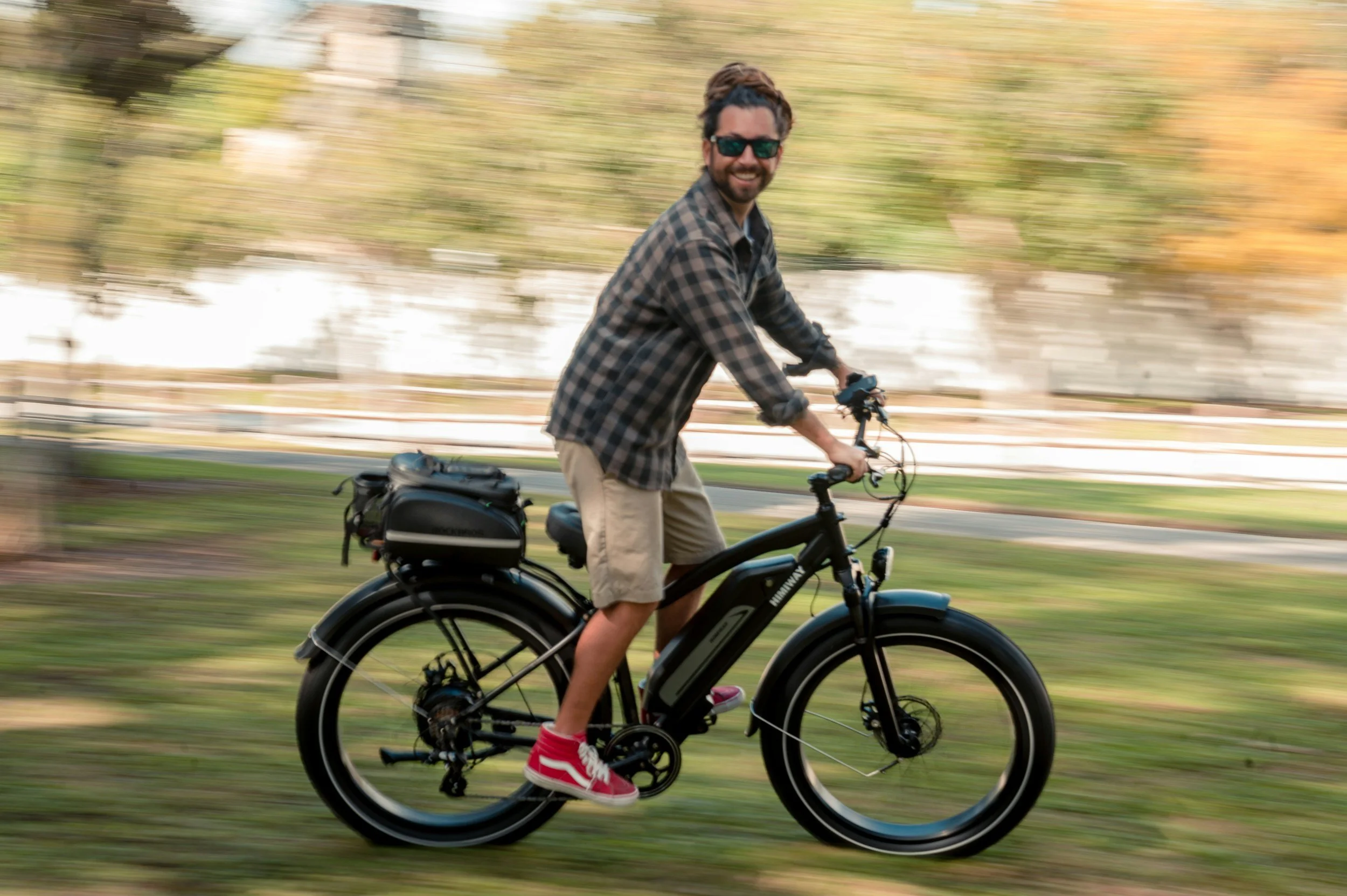 a smiling man riding his electrical bicycle looking straight at the photographer