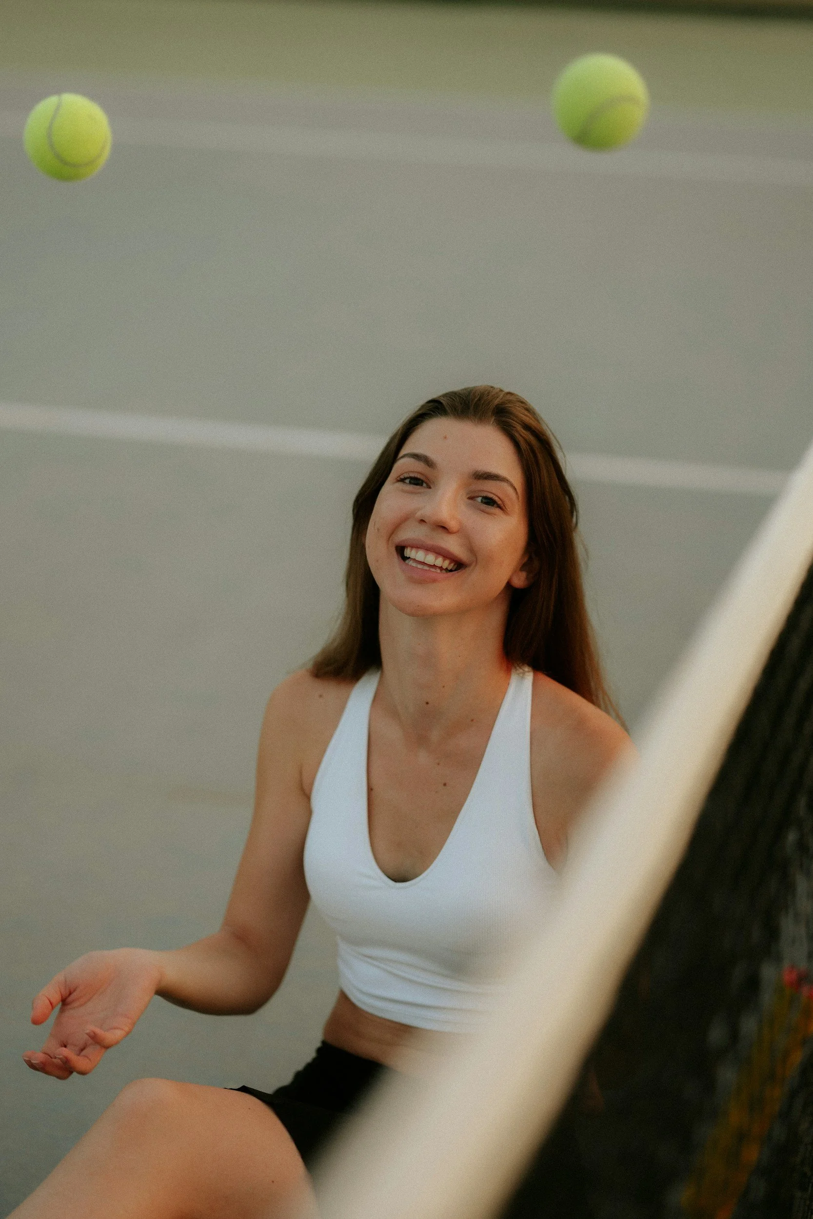 a woman smiling next to a padel court net