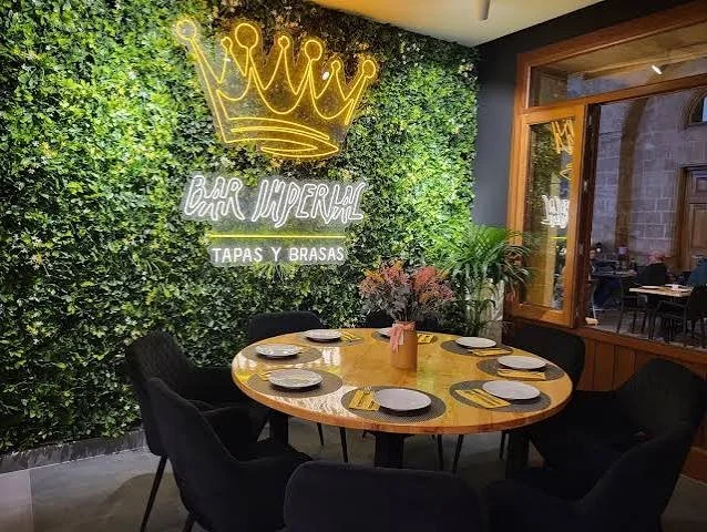A round table in front of a green wall at Bar Imperial in Jávea