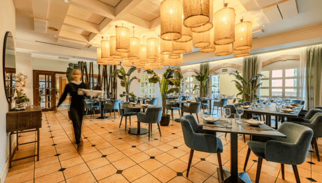 A lounge area with several tables in La Nao Lounge at Dénia Marriott La Sella Hotel