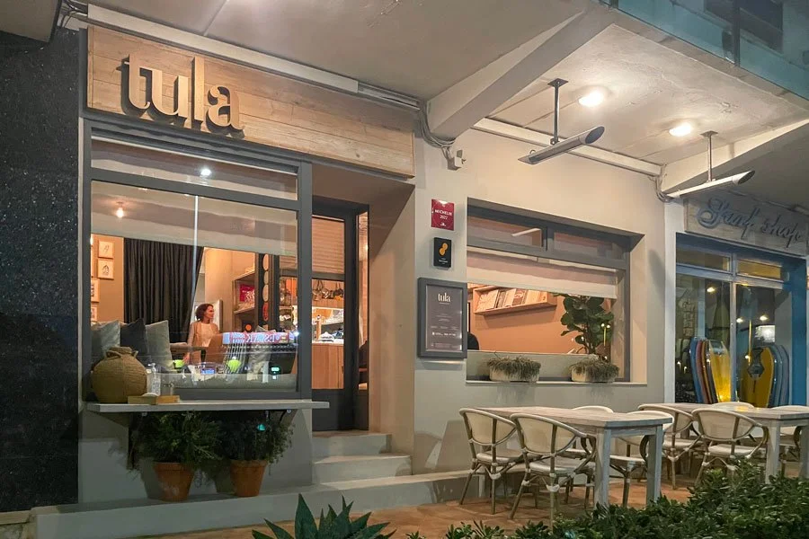 The facade of Tula restaurant in Jávea with an outdoor table and green plants in the foreground