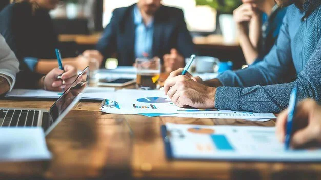 Møte med personer som diskuterer og vurderer dokumenter og diagrammer på et konferansebord.
