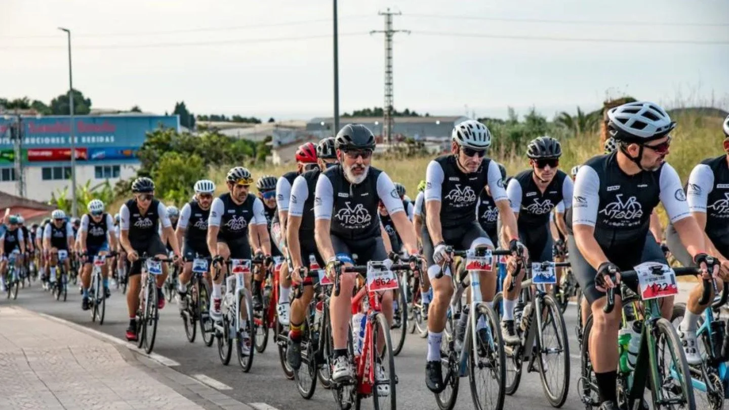 A large group of cyclists in black and white uniforms participating in a roadcycling race