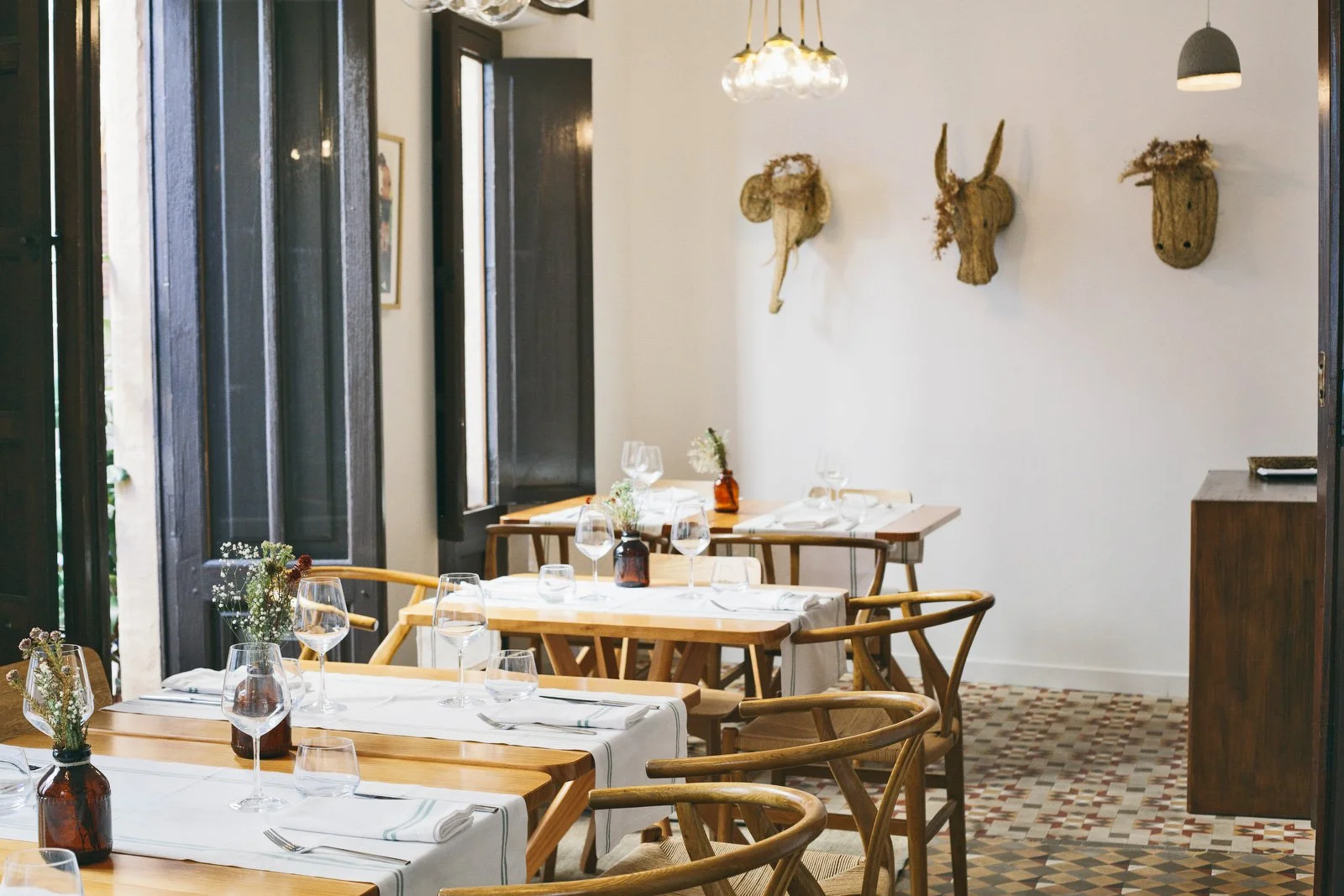 Three set tables with a white wall i the background at Volta i Volta restaurant in Jávea