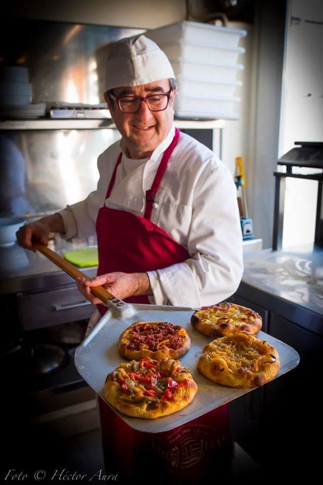 A chef holds four cocas on an oven spade at Pont Sec restaurant near Dénia
