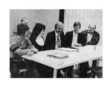 Group of six people sitting at a table in a meeting room.