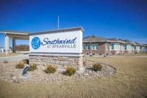 Signboard for Southmound of Spearville with a blue logo, situated in front of a modern building under a clear blue sky.