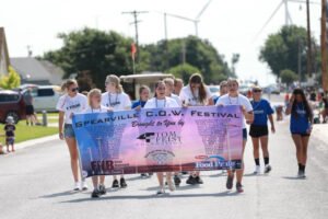 Group of people walking on street holding a banner for the Spearfish C.O.W. Festival.
