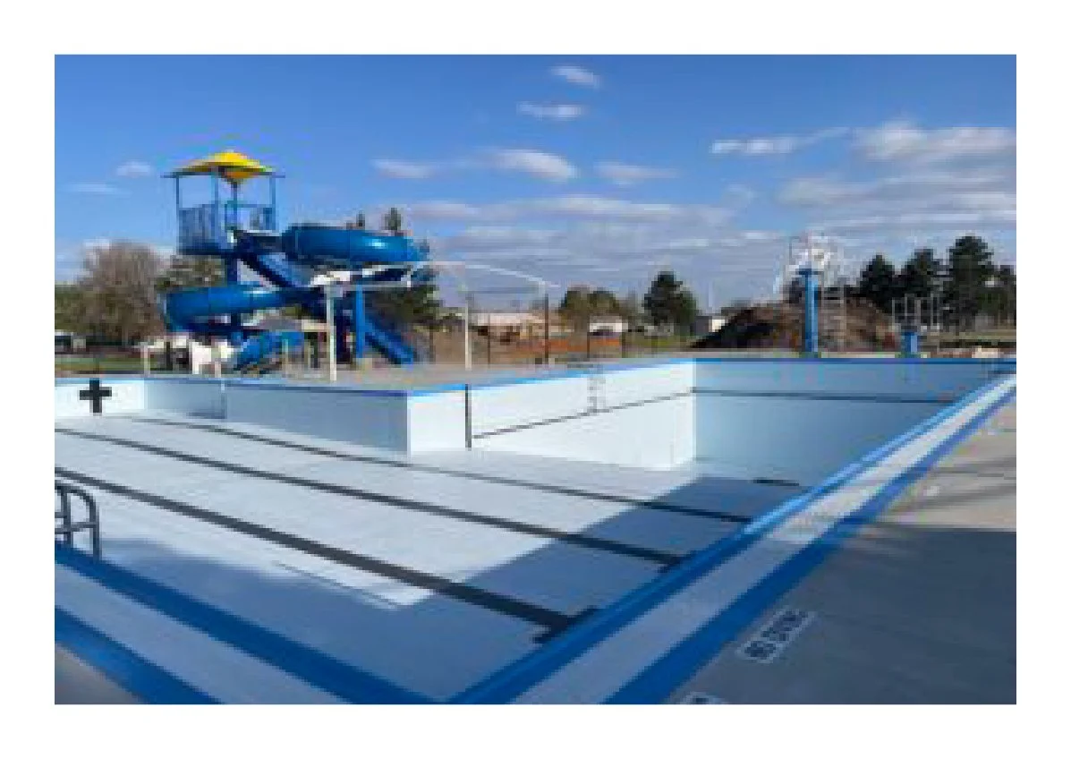 Empty outdoor swimming pool with a water slide in a sunny park