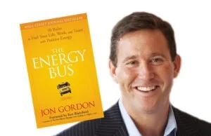Book cover titled 'The Energy Bus' by Jon Gordon placed next to a smiling man in a suit.