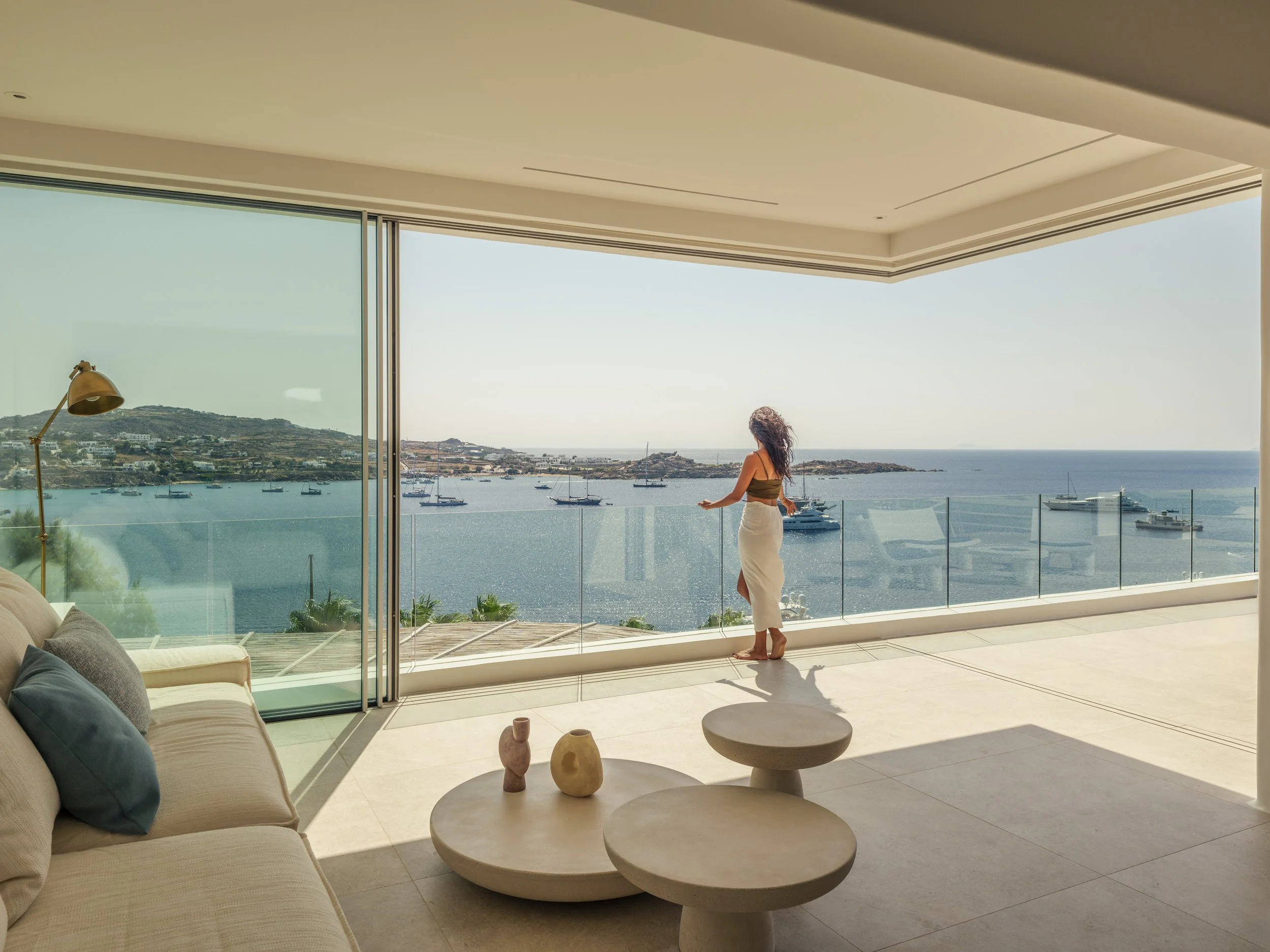 Woman standing on balcony overlooking a harbor with boats in the water.