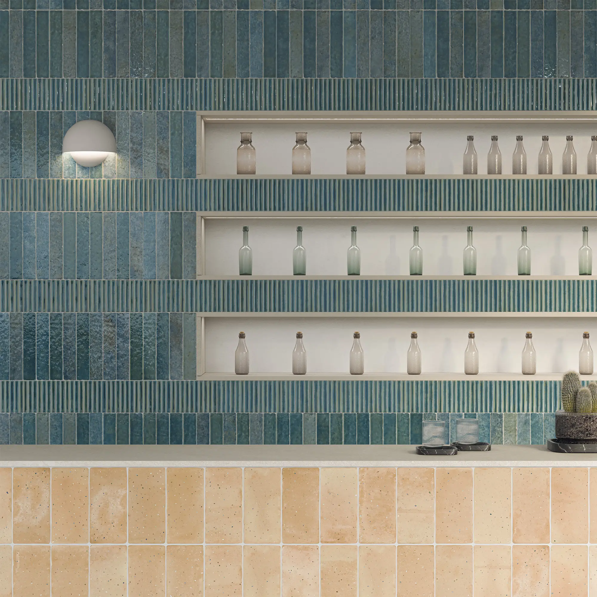 Estantería con botellas de vidrio y una lámpara de pared, decorada con azulejos en tonos azules y beige.