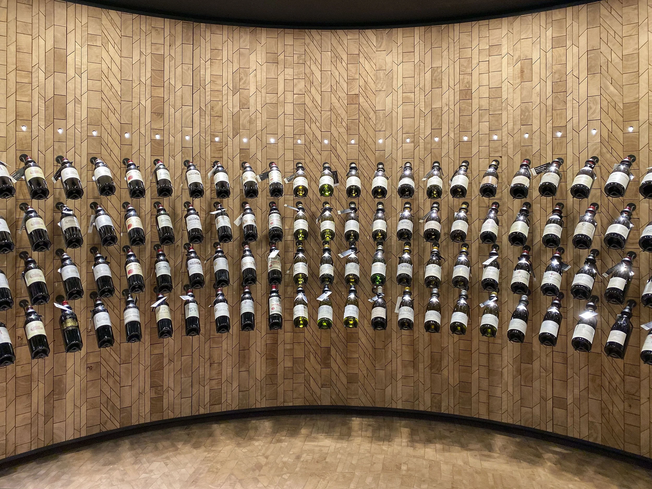 Vitrina con varias botellas de vino en una pared de madera.