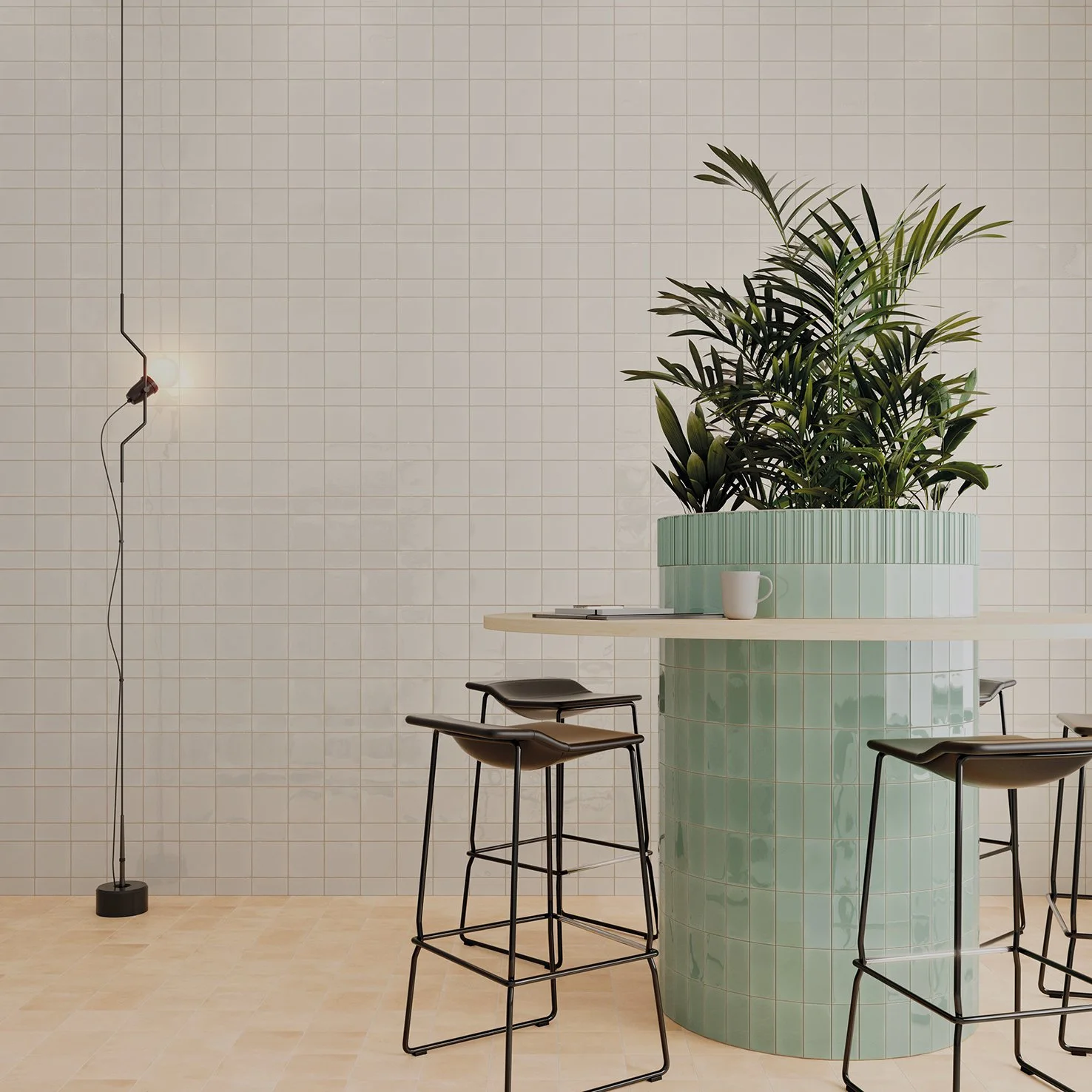 Espacio interior con paredes de azulejos blancos, mesa redonda con pufs negros, planta grande en un macetero verde y lámpara de piso